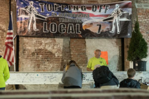 About a hundred construction workers and college officials gathered on the first floor of Little Building to celebrate the placement of the building's last iron beam. Cullen Granzen / Beacon Staff