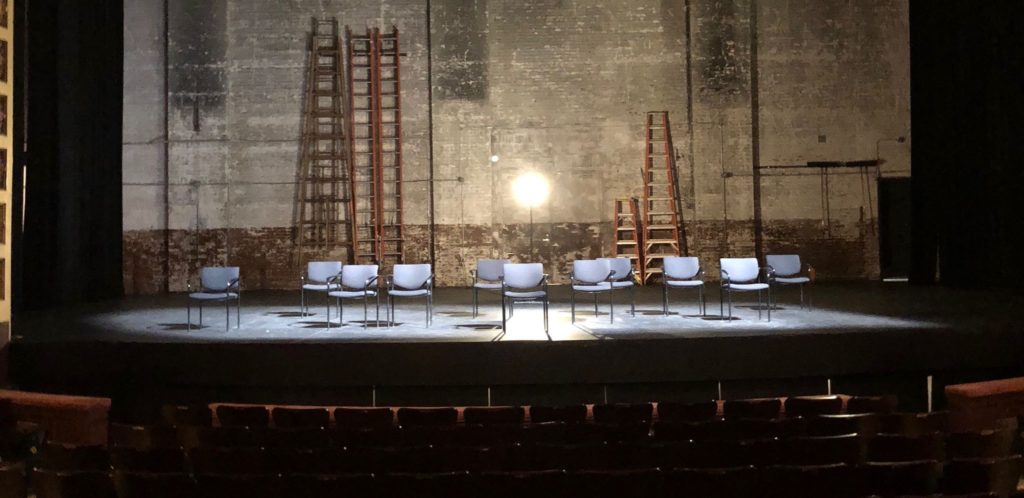 Eleven chairs rested empty in the middle of the stage lit by a solitary spotlight to represent the 11 people killed in the synagogue in Pittsburgh. Photo by Stephanie Purifoy / Beacon Staff. 