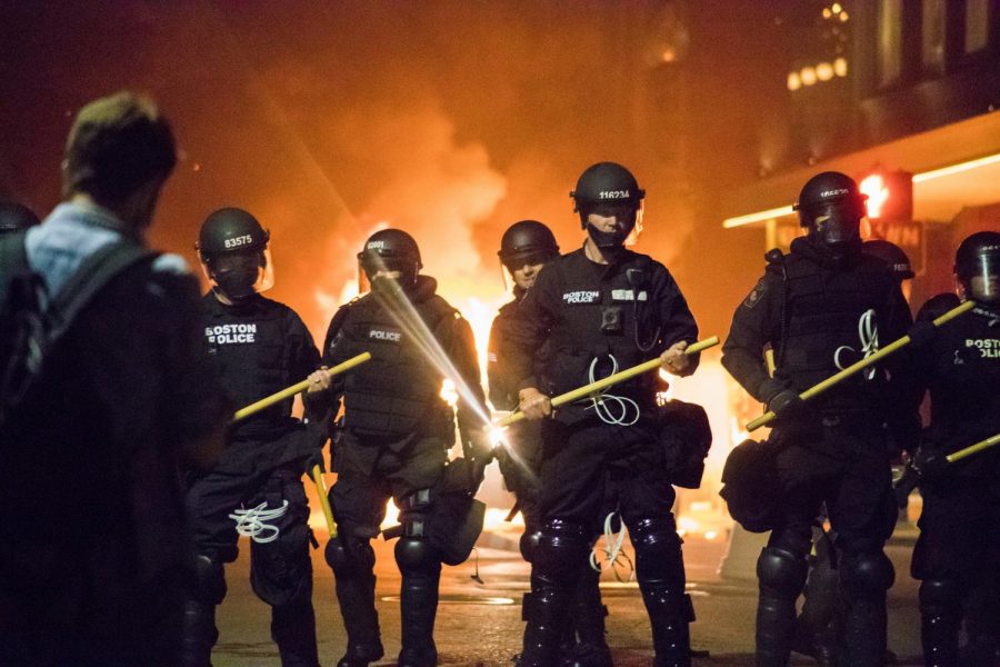 Officers stand in front of a burning police car on Tremont Street.