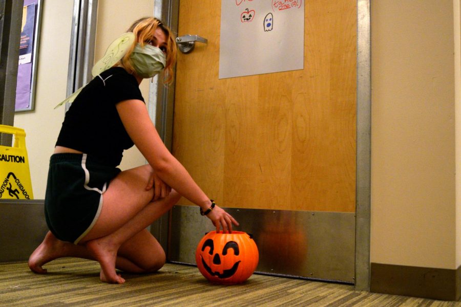 Megan Quirk sets up a plastic pumpkin basket outside a Colonial dorm in preparation for Halloween.