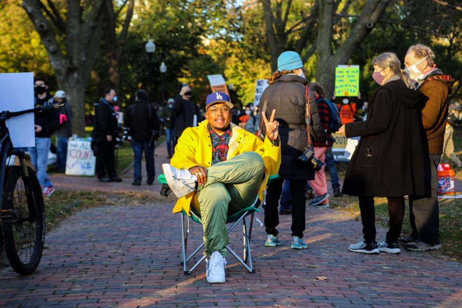 A man sits in a chair watching the Count Every Vote rally in the Boston Common on Wednesday.