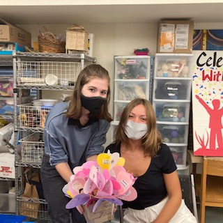 Elly Bryant and Olivienne Redding at their volunteer shift holding “kindness flower” made in the art studio for guests.  