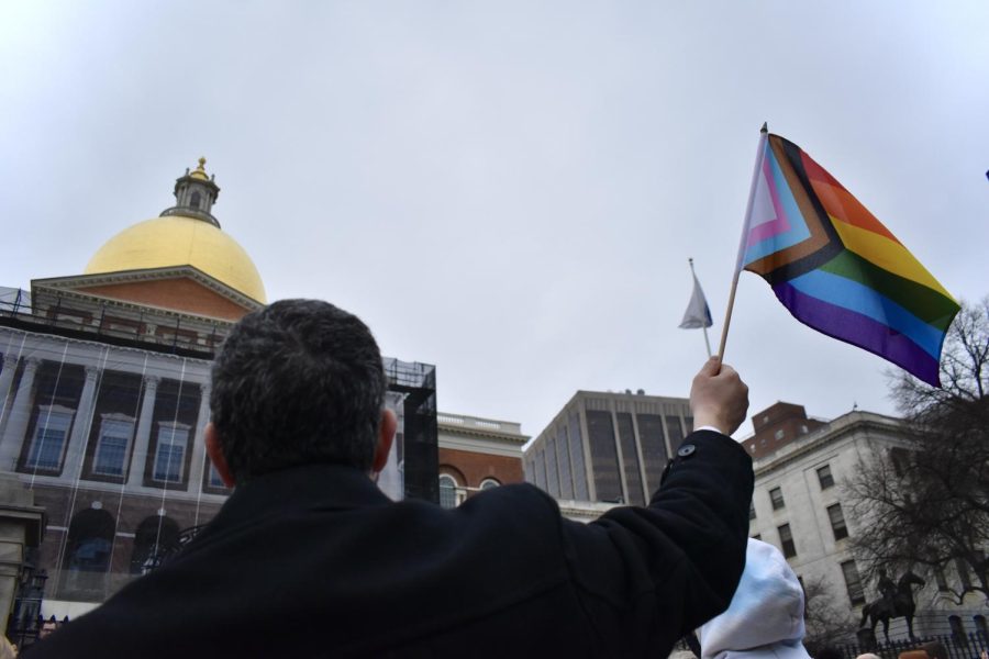 A person waves a pride flag in support of trans youth.