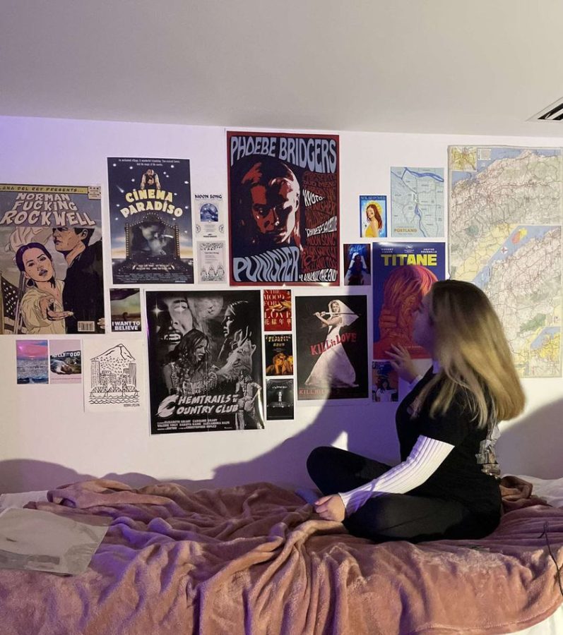 Writer Karenna Umscheid sits on her dorm bed, looking at the posters on her wall.