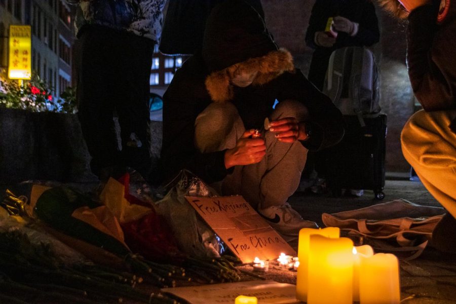 A person kneels while lighting a candle for the candlelight vigil.