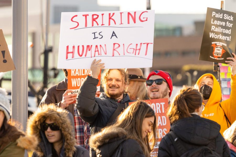 A protester holds up a sign that reads “Striking is a human right” surround by other protesters and signs.