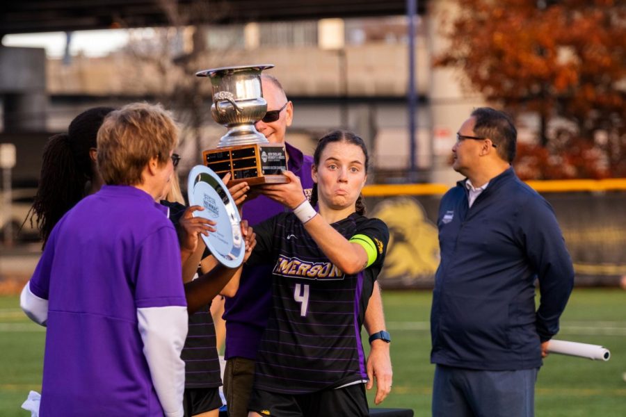 Senior+Cali+Bruce+raises+the+womens+soccer+teams+first-ever+NEWMAC+Championship+cup.
