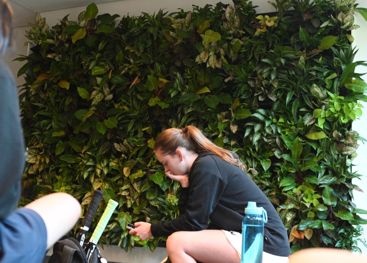 Members of the tennis team chat in front of the new plant wall in the Piano Row lobby. (Amin S. Lotfi for The Beacon)