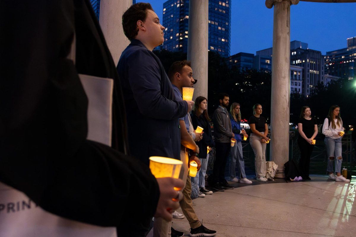 Community members gather in the Parkman Bandstand holding candles. (Arthur Mansavage/Beacon Staff)