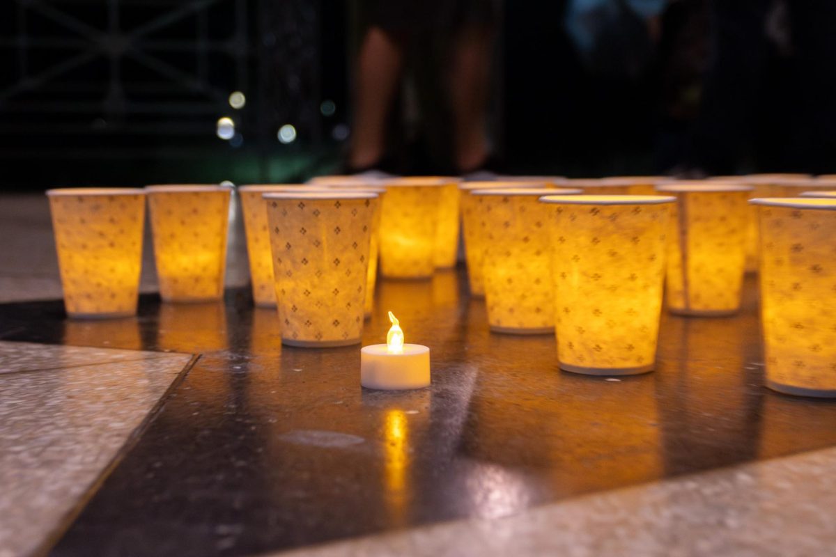A bundle of flickering battery candles placed on the ground of the Parkman Bandstand. 