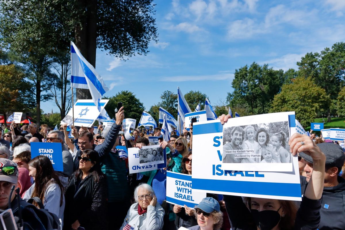 A crowd of Israel supporters in the Boston Commons waving flags and signs, creating a sea of blue and white.