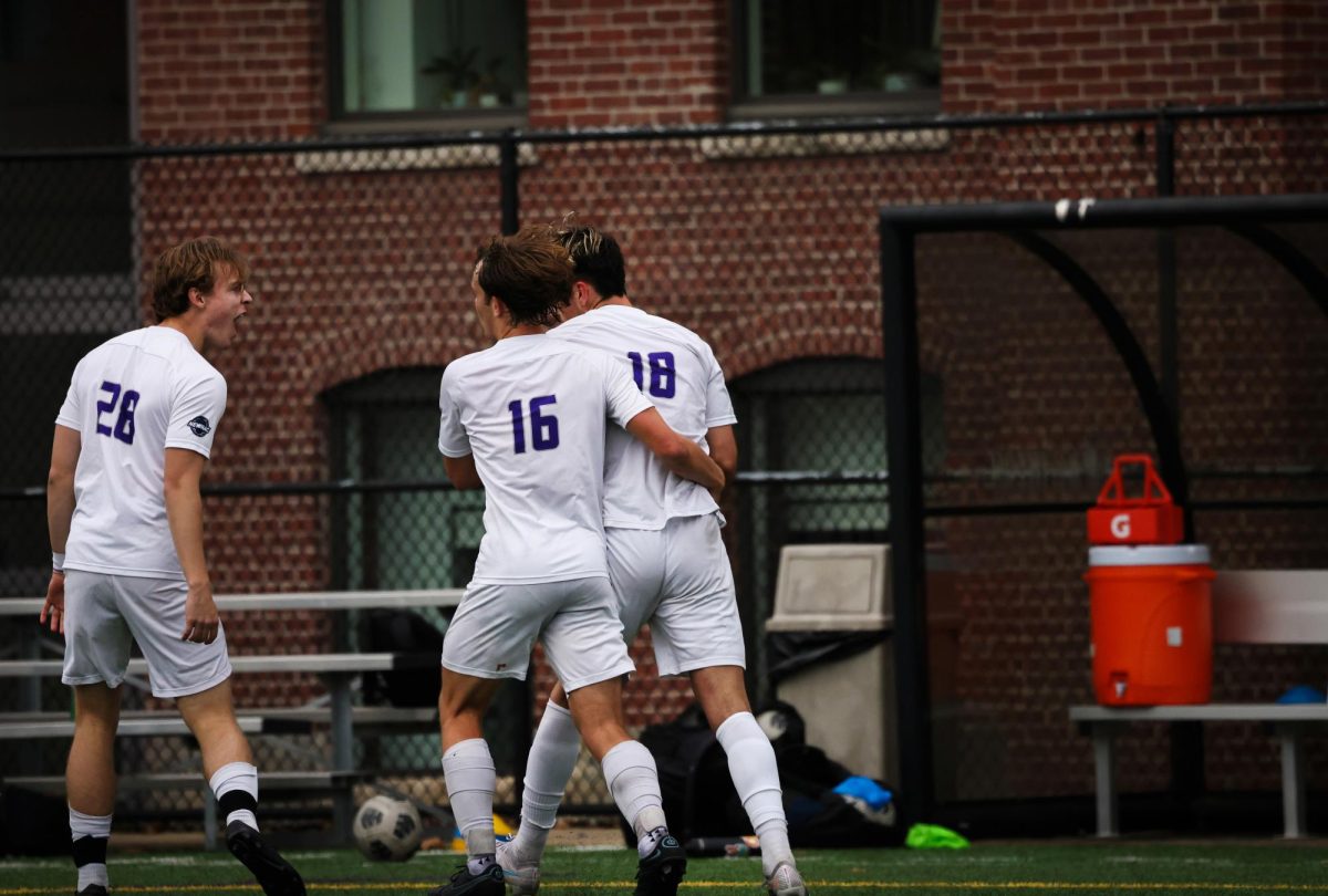 Emersons Rohan Edwards (28), left, Aidan Ferguson (16), center, Thomas Pelino (18), right, celebrate as Thomas Pelino (18) scores a goal to help Emerson to a 2-2 draw with MIT at Rotch Playground in Boston, on Saturday, Oct. 14, 2023. (Ashlyn Wang/Beacon Staff)