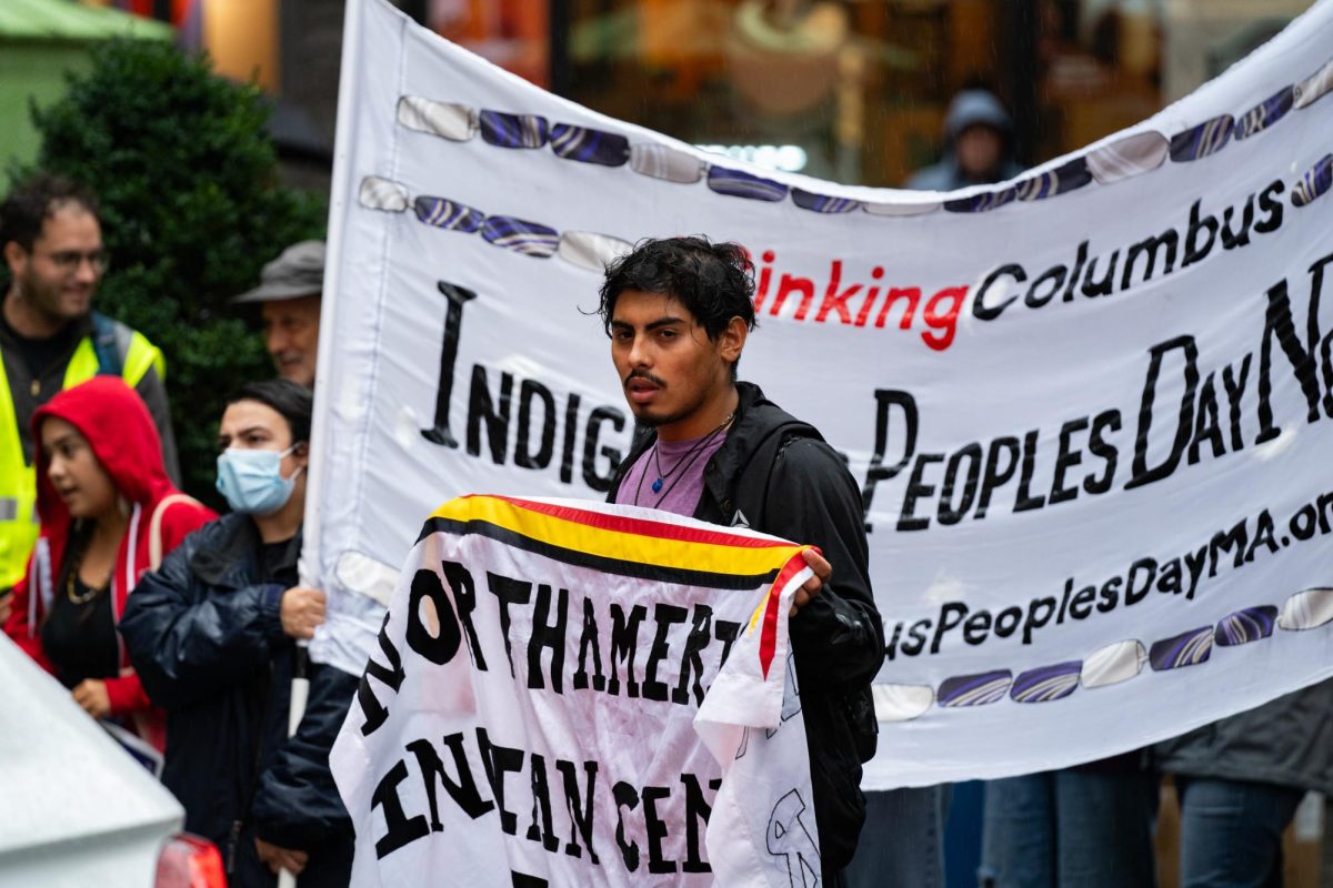 A protester holds a banner of the North American Indian Center of Boston as protesters walk down Washington Street. (Zubin Stillings for The Beacon)
