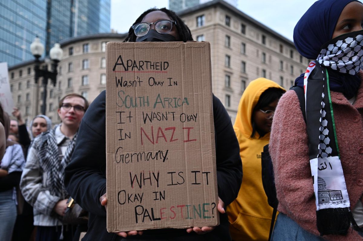A rally-goer holds up a sign that reads “Apartheid Wasn’t Okay In South Africa. It Wasn’t Okay In Nazi Germany. Why Is It Okay In Palestine?” on Wednesday, Oct. 25, 2023, in Copley Square.