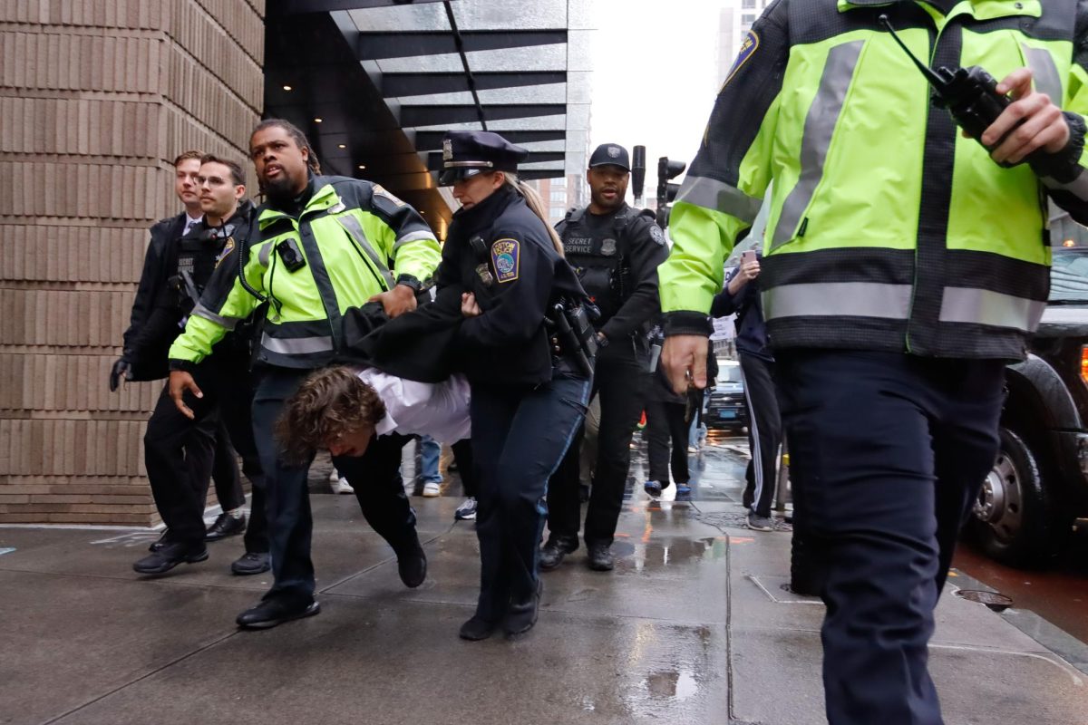Boston Police and Secret Service agents carry a protester by their arms and legs away from the outside of the Ritz-Carlton hotel ahead of Vice President Kamala Harris’s visit to Downtown Boston on Thursday, Nov. 9, 2023.