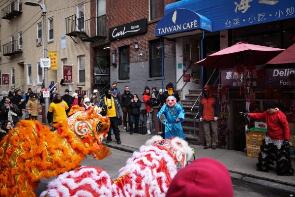 A group of performers arrive in front of the Taiwan Café, a Chinatown catering business, while lion dancers bow three times in gratitude as the restaurant offers oranges and cabbages to “feed” them. (Ashlyn Wang/Beacon Staff)