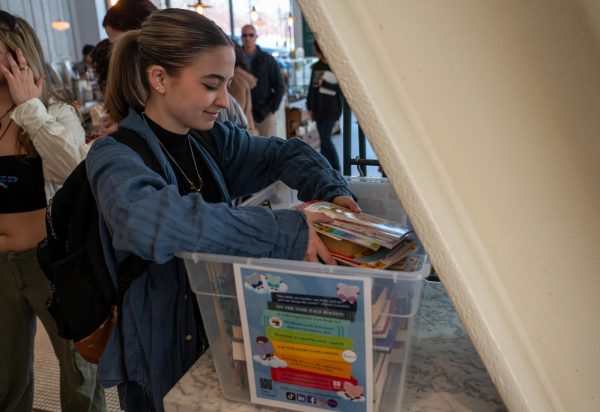 Grace Bickerstaffe, a sophomore at Emerson College, donates books at the Tatte Bakery next to Emerson College on Monday, April 8, 2024. (Feixu Chen/Beacon Staff)