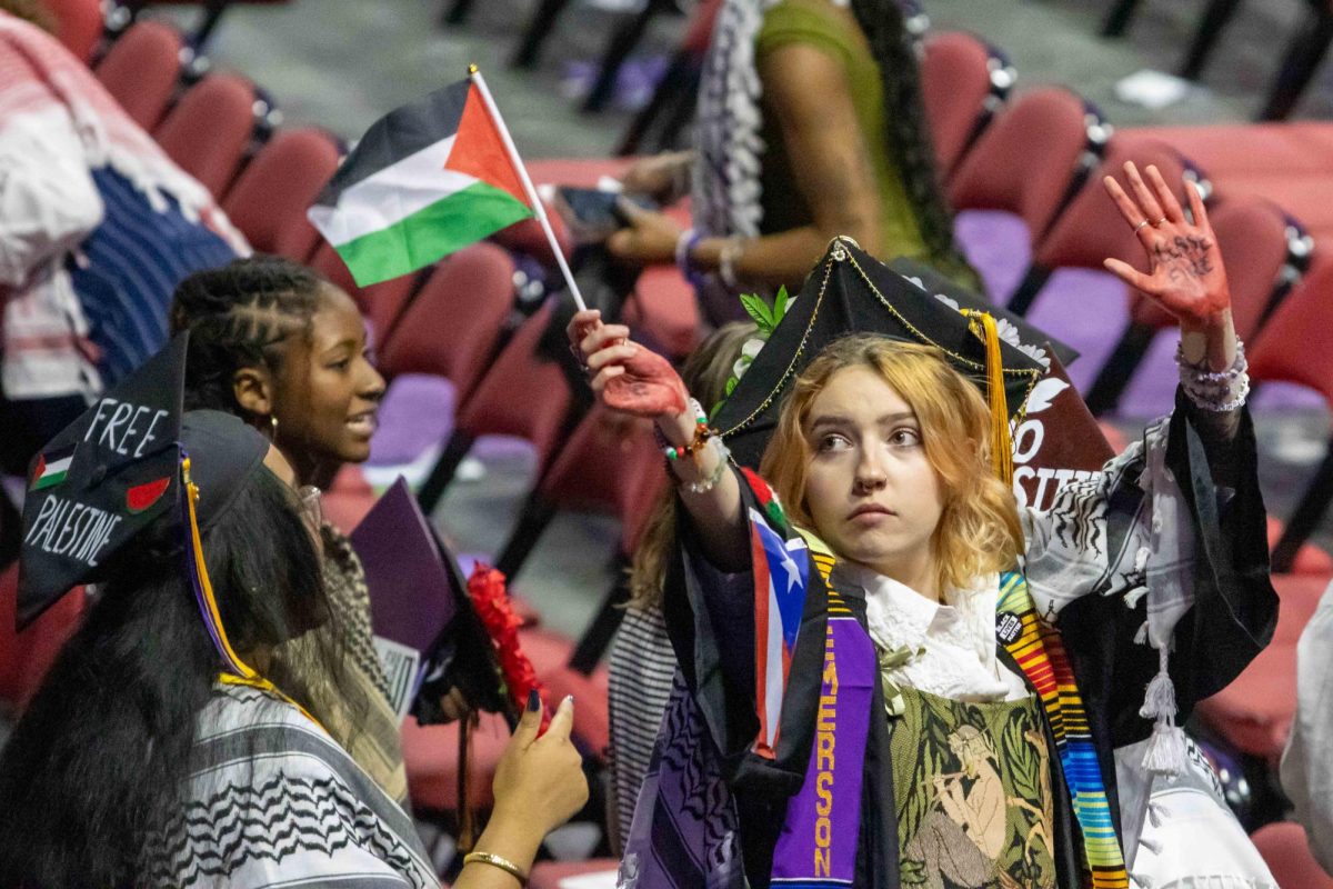 A student waves a Palestinian flag and holds up their hand, on which is written, “Ceasefire now.” (Rian Nelson/Beacon Staff)