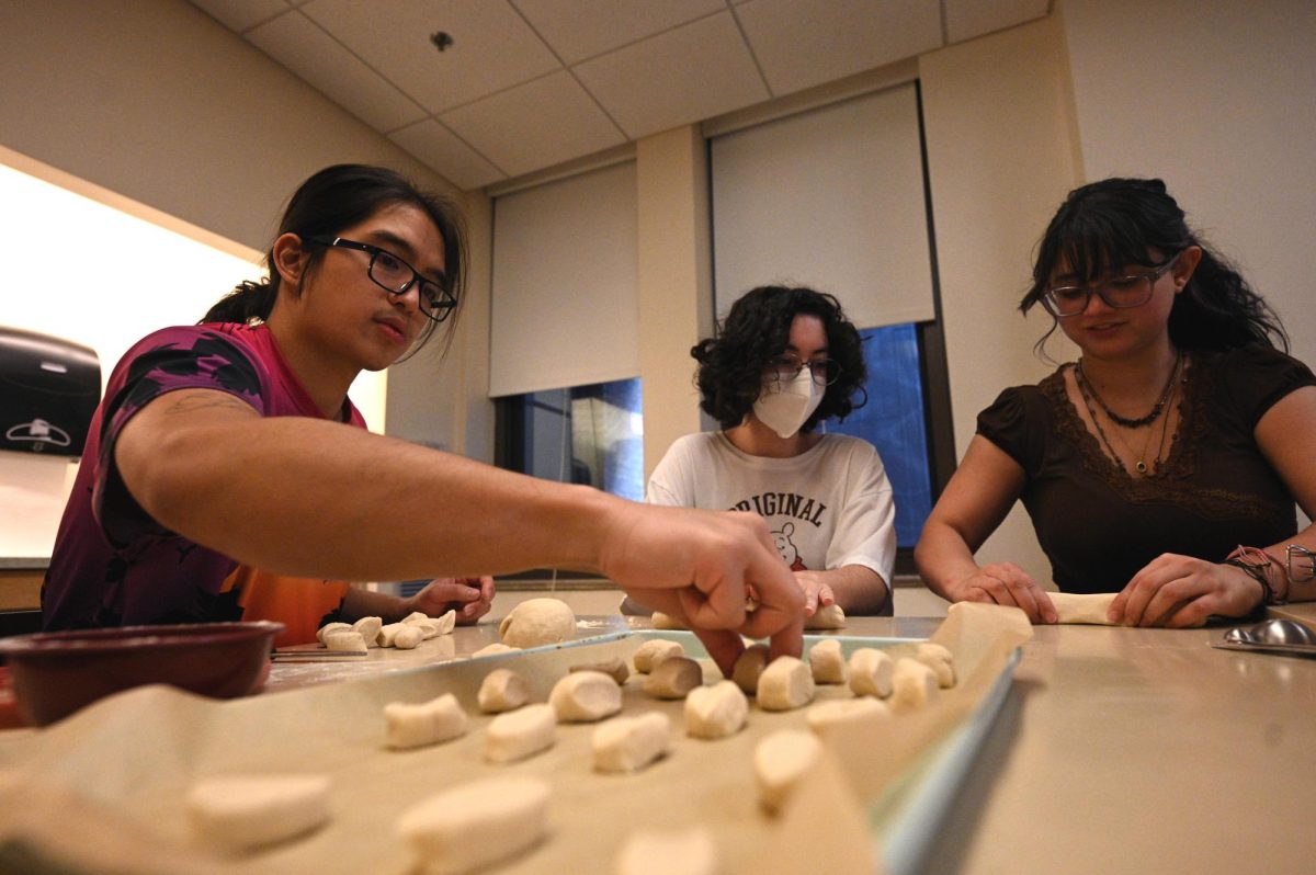 Left to Right: Tomas Macasaet, Kellyn Taylor, and Gabriella Garza work on rolling and cutting dough to make pretzel bites to cater snacks for a meeting for Emerson’s Generic Magazine on September 24, 2024 (Bryan Hecht / Beacon Staff).