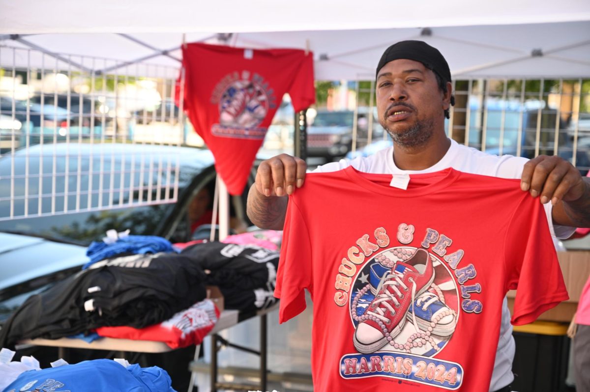 Lajohn Robinson, a t-shirt vendor from Mobile, Alabama, holding his Kamala Harris merch on September 10, 2024 (Bryan Hecht / Beacon Staff). 