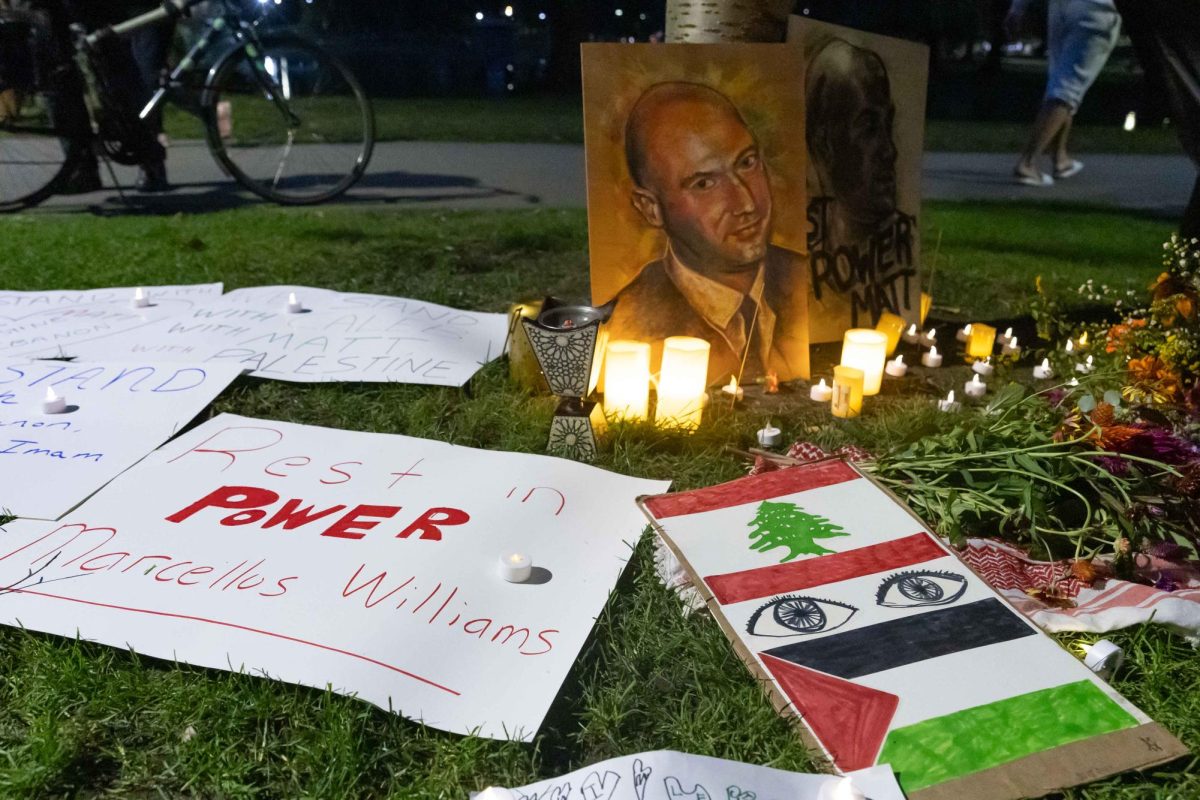 Community members placed artwork and candles under a tree that had a Palestinian flag draped over it to honor Matthew Nelson. (Rian Nelson / Beacon Staff)