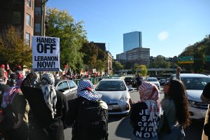 Protesters hold signs and yell chants as they demonstrate on Storrow Drive, halting traffic on October 6, 2024 (Bryan Hecht / Beacon Staff).