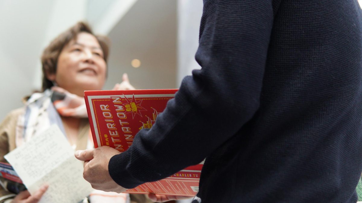 Charles Yu signs local author Cynthia Yee's copy of "Interior Chinatown" at the Boston Asian American Film Festival. Yee writes her own column called the Hudson Street Chronicles, a collection of personal essays about growing up in Boston's Chinatown during the '60s. She says the book saved her life. (Bryan Liu/ Beacon Staff)