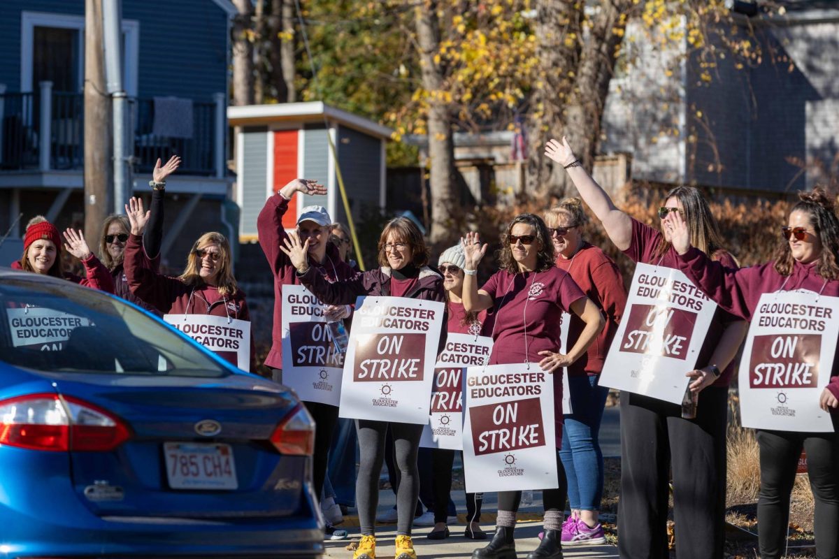 Teachers and other educational staff on strike wave as cars honk in support. (Rian Nelson/ Beacon Staff)