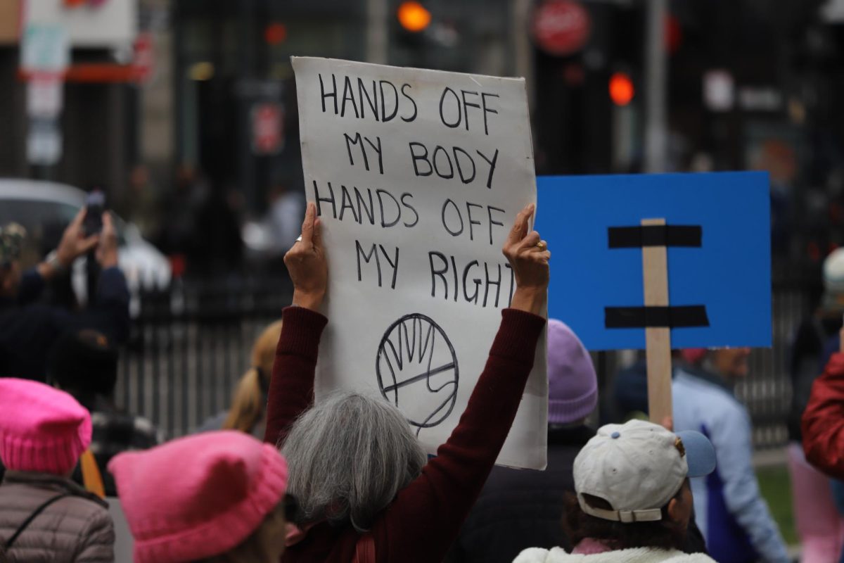 An attendee holds up a sign that reads "Hands off my body. Hands off my rights."