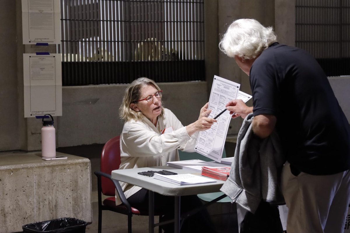 A poll worker passes a empty ballot to a voter at the Massachusetts State House on Tuesday, Nov. 5. (Arthur Mansavage/ Beacon Staff)