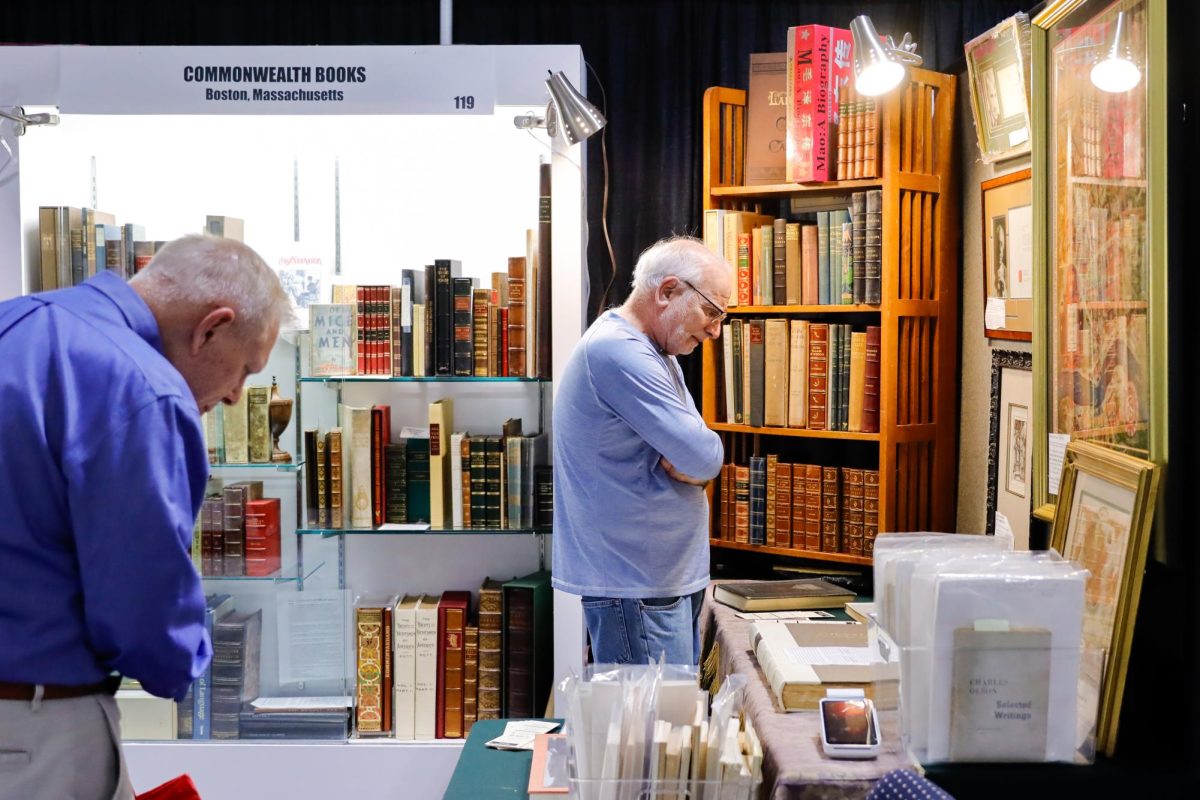 An attende browses the Commonwealth Books booth at the International Antiquarian Book Fair on Friday, Nov. 8. (Arthur Mansavage/ Beacon Staff) 