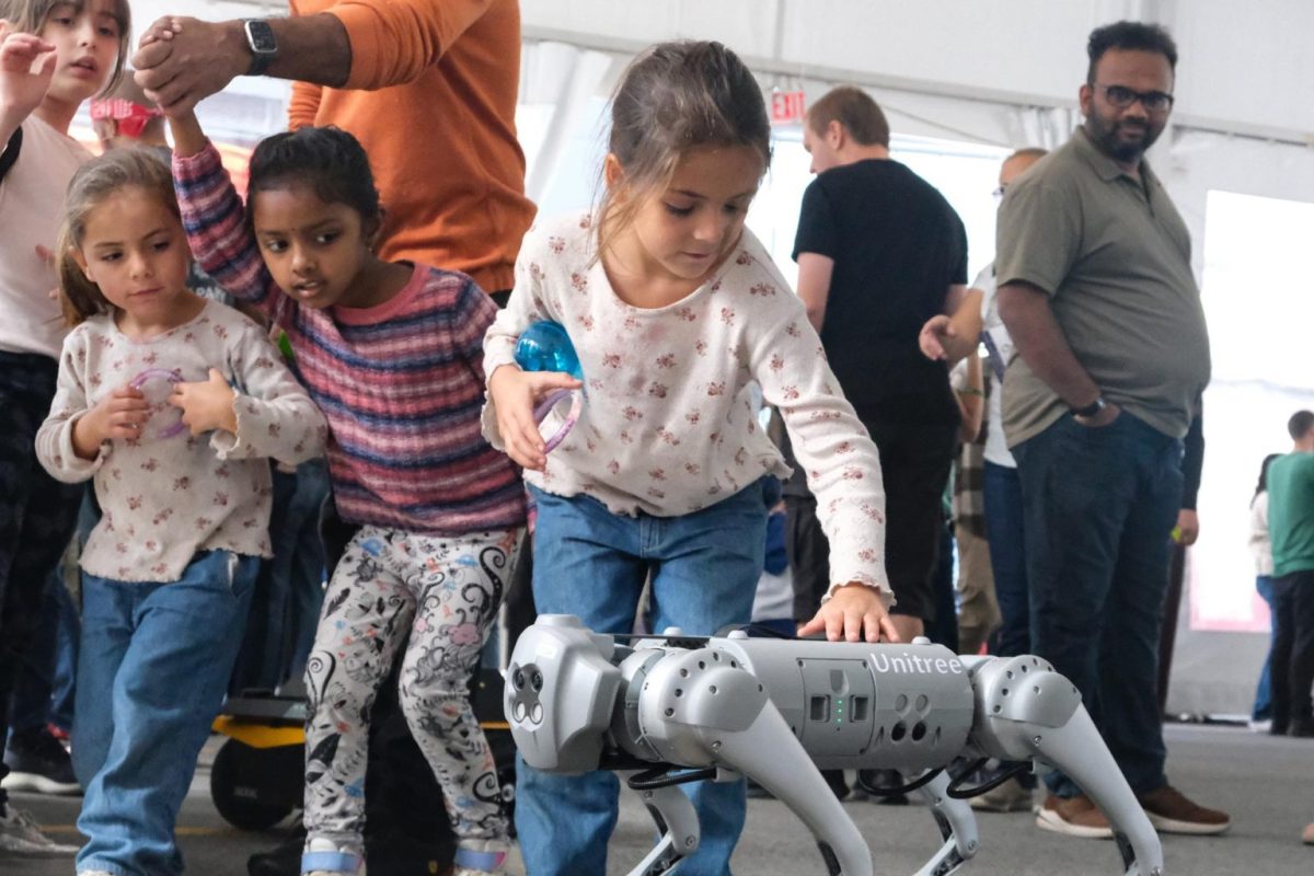 A girl pets a robot dog at Seaport Boulevard during the 7th annual Robot Block Party on Saturday, Sept. 28, 2024. (Julianna Jemima Badajos for The Berkeley Beacon)

