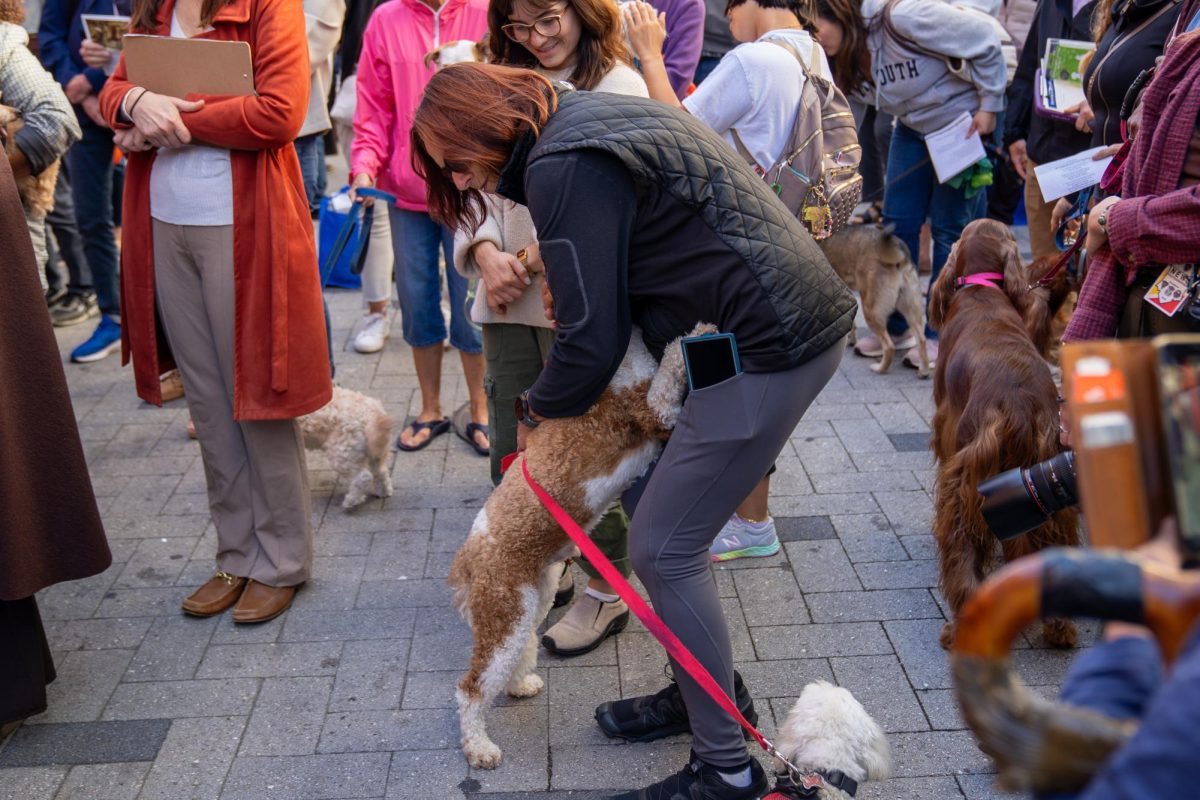 A citizen and a dog hug at the blessing of the animals event at Summer Street Plaza on Sunday, Oct. 6, 2024. (Feixu Chen/Beacon Staff)