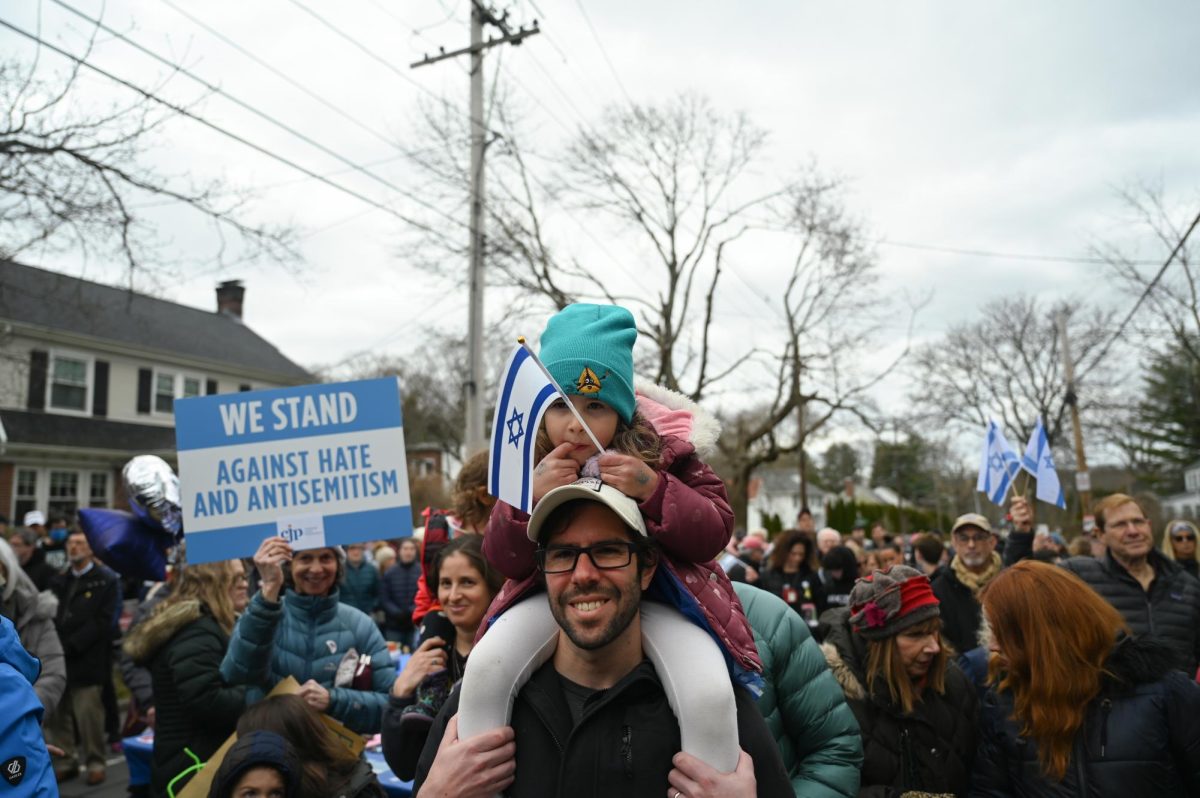 A father and a daughter are among the crowd of thousands carrying Israeli flags during an event on  Sunday, April 7, 2024 rededicating a wall of Hamas’ captives after it was vandalized. (Margaux Jubin for The Berkeley Beacon) 