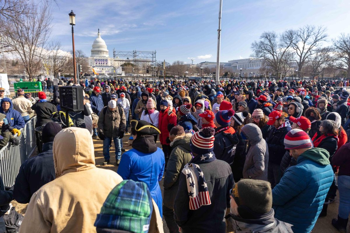 A small crowd gathers around a speaker broadcasting President Trump’s inaugural speech on Monday, Jan. 20, 2025. (Rian Nelson/Beacon Staff)