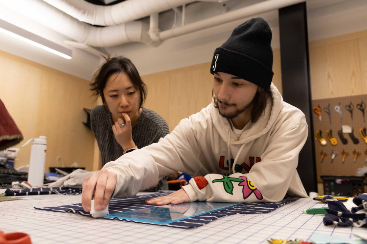 Antonio mateo Garcia (right) teaches Lina Michida how to mark their fabric with chalk. Garcia is the founder of HELP by AMG and was running a workshop on up cycling clothing and scrap fabric. (Rian Nelson/ Beacon Staff)