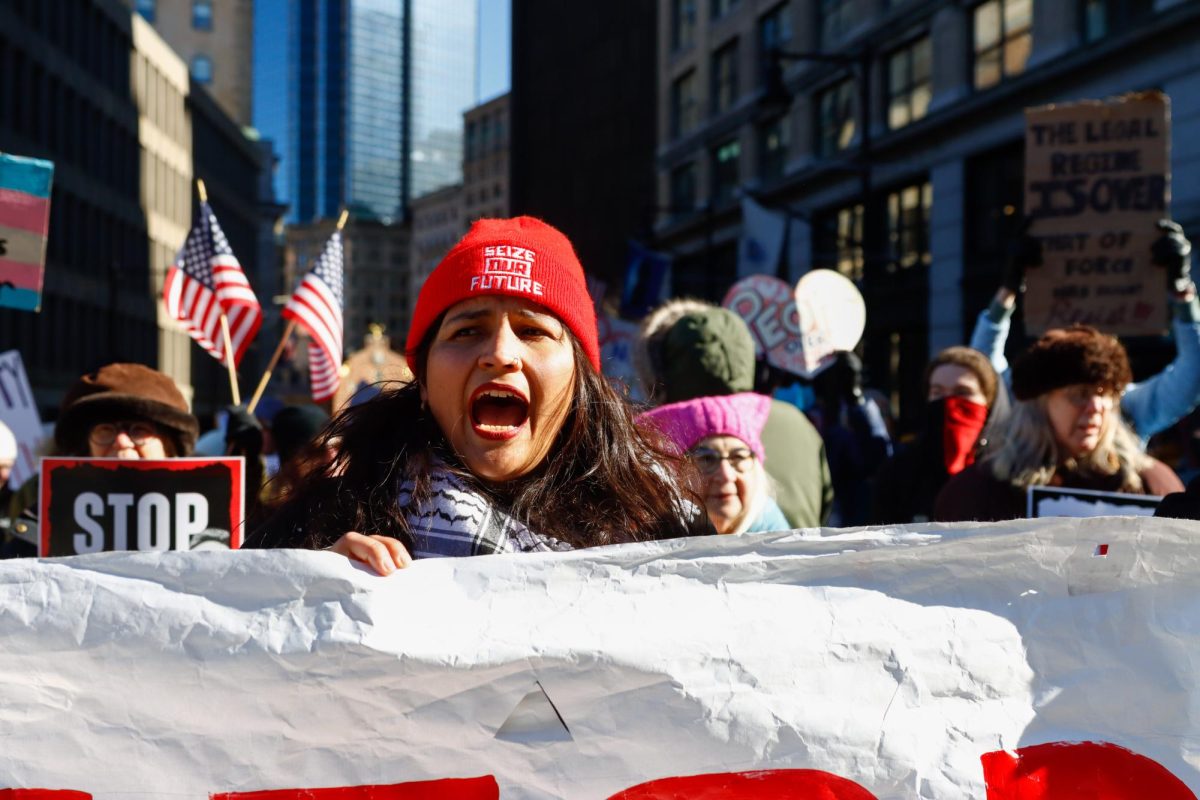 Estefania Galvis, one of the organizers of the rally, shouting and leading the crowd of over a thousand people through the streets outside of Boston city hall plaza on Friday, Feb. 14, 2025. (Arthur Mansavage/ Beacon Staff)