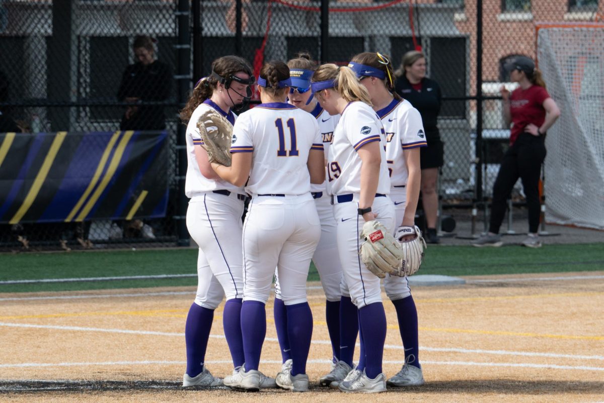 The Emerson softball team in a huddle during a doubleheader vs. MIT on April 25 (Riley Goldman/ Beacon Staff).