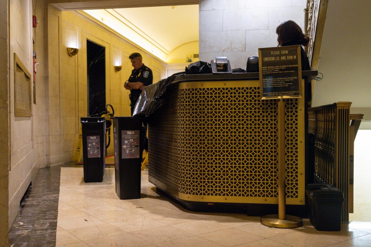 An ECPD officer stands guard in the lobby of Ansin as trash cans catch falling water droplets on Monday evening. (Arthur Mansavage/Beacon Staff)