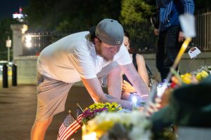 Chris Grey, 41, a construction worker from Quincy Massachusetts places a candle on the steps of the State House. (Arthur Mansavage/Beacon Staff)