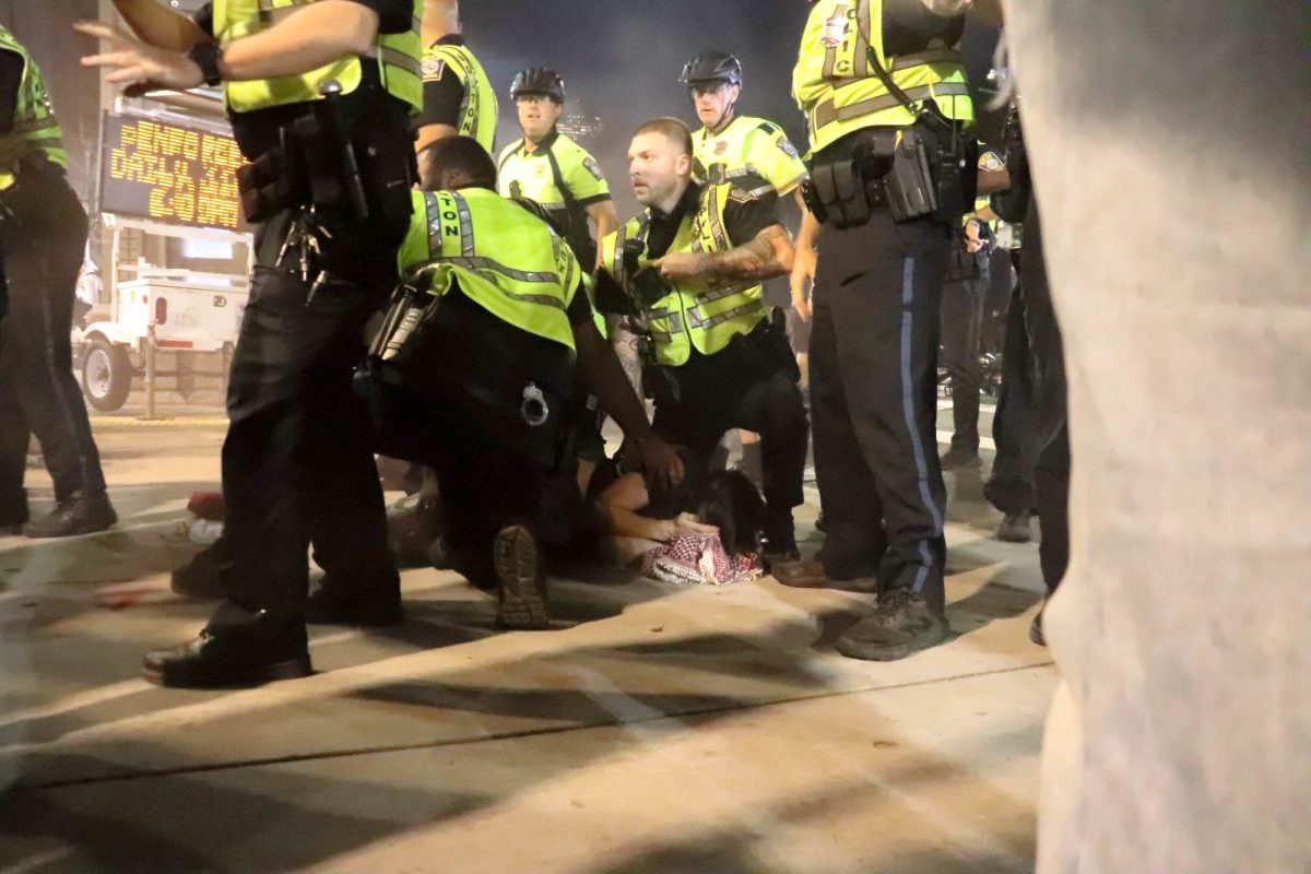 A protester covers their eyes as they are held down and detained by Boston Police officers following a pro-Palestine protest on Tuesday, Oct. 7, 2025. (Bryan Hecht / Beacon Staff)