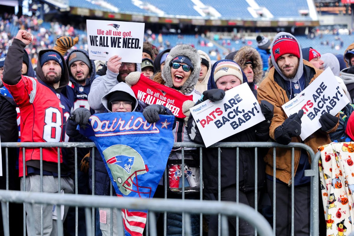 Patriots fans cheer and hold up signs on the field at Gillette Stadium in Foxborough, Mass. on Sunday, Feb. 1, 2026. (Arthur Mansavage/ Beacon Staff)