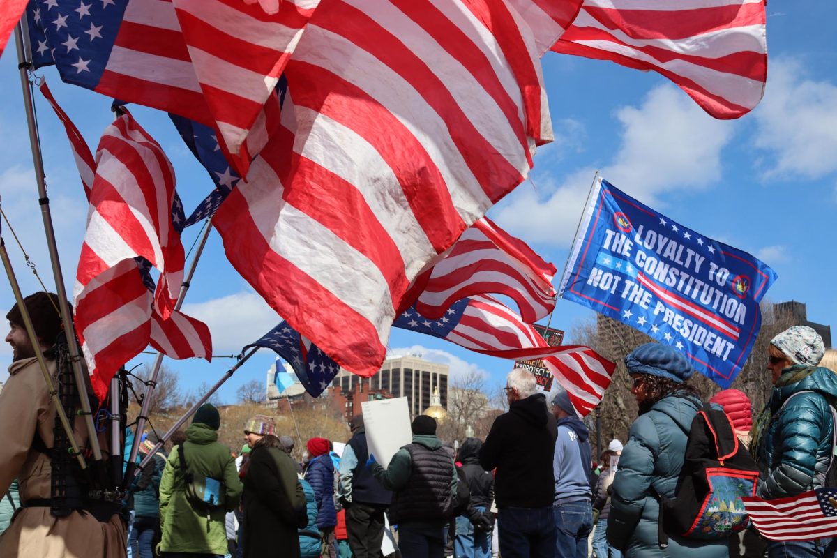 A man walks through Boston Common with multiple upside-down U.S. flags attached to his back. (Avary Amaral/ Beacon Staff)